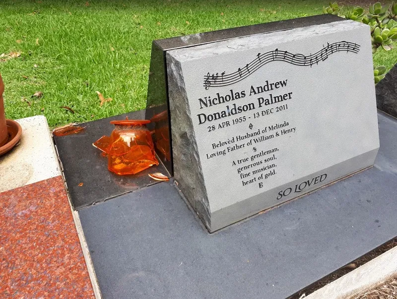 Desk-style headstone for Nicholas Andrew Donaldson Palmer with a music stave, raised inscription and honed base