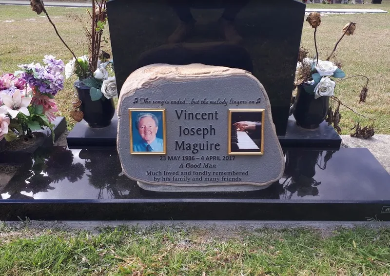 Basalt boulder memorial for Vincent Joseph Maguire with a raised inscription and two colour ceramic photos on a black granite base